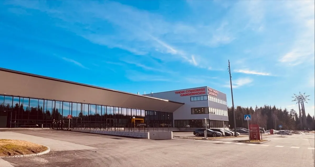 Thon Congress Gardermoen sett fra parkeringsplassen en solrik dag med blå himmel