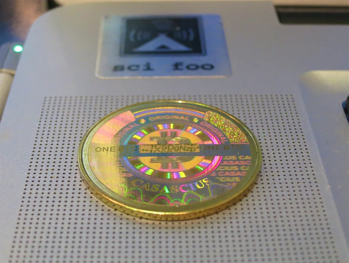 En forgylt Casascius-mynt med bitcoinsymbolet og et hologram som dekker en privat nøkkel