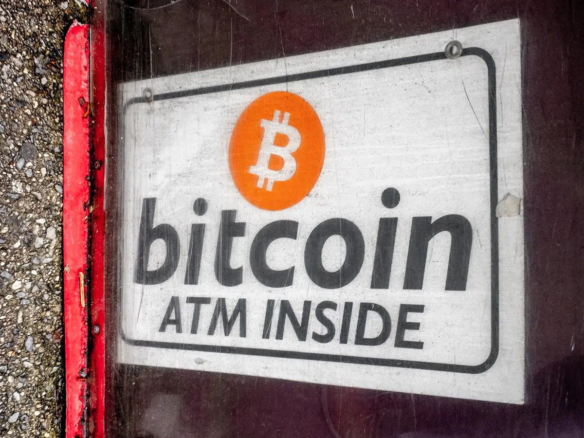 Et slitt skilt i et butikkvindu med bitcoinlogoen og teksten «bitcoin ATM inside»