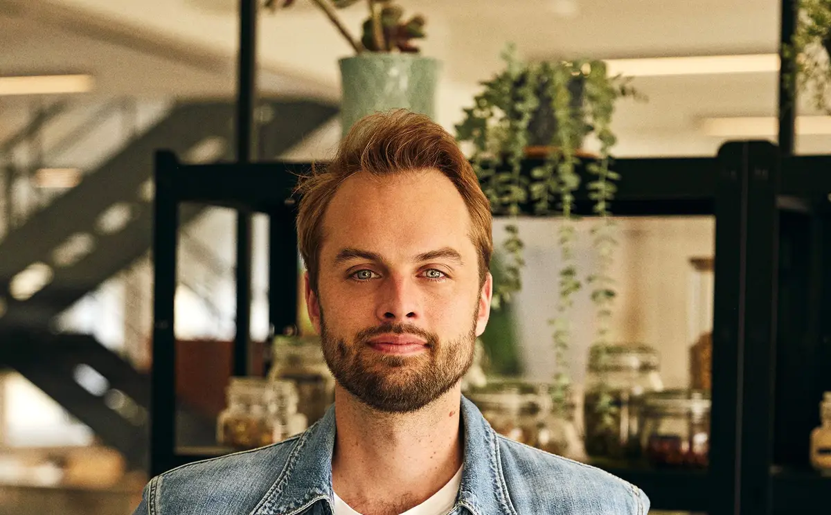 Kristian Hald står med hendene i siden foran en glasshylle med krydderglass