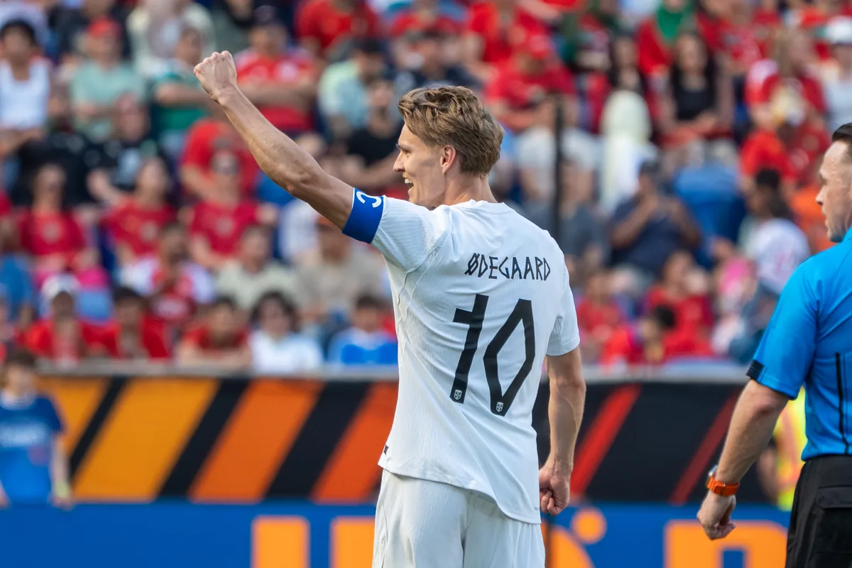 Martin Ødegaard med kapteinsbindet på venstre arm og ryggen mot kameraet, i hvit landslagsdrakt med nummer 10
