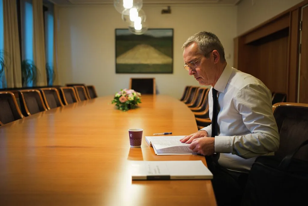 Jens Stoltenberg sitter alene ved et langt møtebord og leser i budsjettdokumentet før framleggelsen